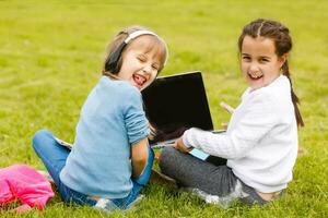 Due divertente studentesse sedersi su il erba e leggere libri. ragazze, amiche, sorelle siamo insegnato Lezioni nel natura. foto