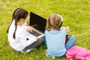 Due divertente studentesse sedersi su il erba e leggere libri. ragazze, amiche, sorelle siamo insegnato Lezioni nel natura. foto