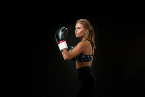 bellissimo femmina atleta nel boxe guanti, nel il studio su un' nero sfondo. foto
