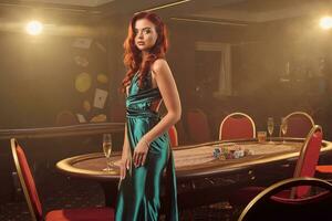 giovane bellissimo donna è in posa contro un' poker tavolo nel lusso casinò. foto