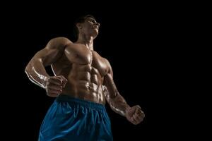 muscolare e in forma giovane bodybuilder fitness maschio modello in posa al di sopra di nero sfondo. foto