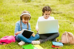 Due divertente studentesse sedersi su il erba e leggere libri. ragazze, amiche, sorelle siamo insegnato Lezioni nel natura. foto