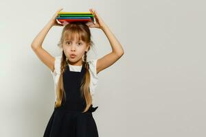 poco divertente ragazza nel camicia con libri. isolato su bianca sfondo. bambino ragazza nel scuola. il bambino ragazza con libri di testo. ragazza studiare. foto