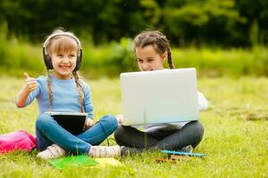 Due divertente studentesse sedersi su il erba e leggere libri. ragazze, amiche, sorelle siamo insegnato Lezioni nel natura. foto