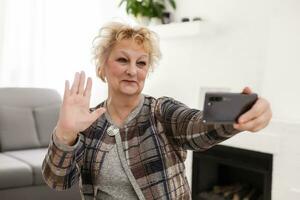 anziano donna utilizzando toccare schermo mobile per assunzione autoscatto o fabbricazione video chiamata foto