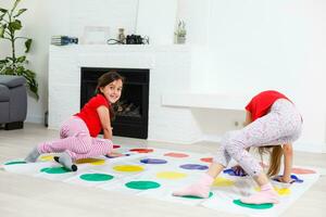 Due contento ragazze nel figli di Abiti con entusiasmo giocare su il pavimento. foto