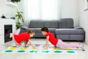 Due poco ragazze avendo divertimento giocando gioco su pavimento a casa. fratelli amicizia foto