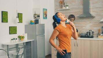 positivo giovane donna cantando su di legno cucchiaio nel il mattina. energico, positivo, felice, divertente e carino casalinga danza solo nel il Casa. divertimento e tempo libero solo a casa foto