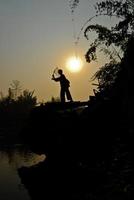 il ragazzo sta sul pontone e pesca foto