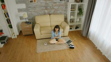 superiore giù Visualizza di donna nel corto jeans lettura un' libro su il pavimento con un' tazza di caffè Il prossimo per sua foto