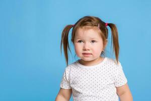 un' carino poco ragazza è sorridente su un' blu isolato sfondo con maiale code per un' felicità o infanzia concetto. foto
