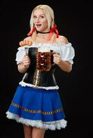 giovane sexy donna indossare un' dirndl con birra boccale su nero sfondo. foto