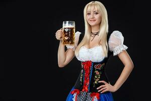 giovane sexy donna indossare un' dirndl con birra boccale su nero sfondo. foto