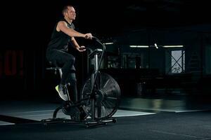maschio che usa la bici dell'aria per l'allenamento cardio presso la palestra di cross training. foto