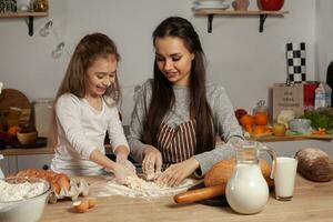 madre e sua figlia siamo cottura al forno un' pane e avendo divertimento a il cucina. foto