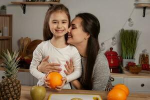 madre e sua figlia siamo fare un' frutta taglio e avendo divertimento a il cucina. foto