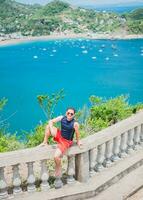 ritratto di turista uomo nel il Visualizza di il baia di san juan del sur. contento turista seduta nel un' punto di vista di un' baia, viaggio e turismo promozione concetto. foto