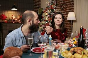 coppia frequentando Natale cena con famiglia, donna festeggiare natale inverno vacanza con amici a festivo evento. persone sensazione contento mangiare cibo e potabile vino a casa. foto