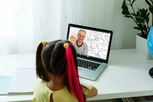 carino poco ragazza utilizzando il computer portatile a casa. formazione scolastica, in linea studia, casa studiando, distanza apprendimento, scolara bambini stile di vita concetto foto