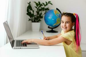 freddo in linea scuola. ragazzo studiando in linea a casa utilizzando un' il computer portatile. allegro giovane poco ragazza utilizzando il computer portatile computer studiando attraverso in linea e-learning sistema. distanza o a distanza apprendimento foto