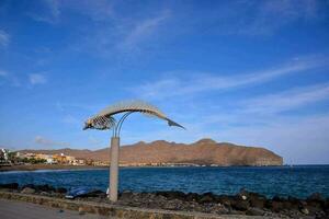 un' scultura di un' pesce su il spiaggia nel davanti di un' montagna foto