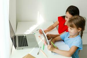 apprendimento a partire dal casa, casa scuola ragazzo concetto. poco bambini studia in linea apprendimento a partire dal casa con il computer portatile. quarantena e sociale distanziamento concetto. foto