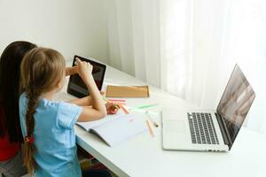 apprendimento a partire dal casa, casa scuola ragazzo concetto. poco bambini studia in linea apprendimento a partire dal casa con il computer portatile. quarantena e sociale distanziamento concetto. foto