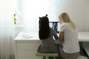 Lavorando a partire dal casa con ragazzo. contento figlia abbracciare madre. giovane donna e carino bambino utilizzando il computer portatile. libero professionista posto di lavoro. femmina attività commerciale, distanza apprendimento. stile di vita famiglia momento. foto