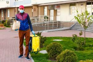 consegna uomo Spedire cibo Borsa a porta pomello per senza contatto o contatto gratuito a partire dal consegna ciclista nel davanti Casa per sociale distanziamento per infezione rischio. foto