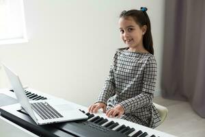 casa lezione su musica per il ragazza su il pianoforte. il idea di attività per il bambino a casa durante quarantena. musica concetto foto