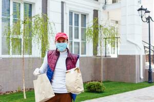 drogheria consegna uomo indossare medico guanti e viso maschera. in linea shopping e consegna per generi alimentari, vino e cibo. se stesso quarantena durante coronavirus pandemia. cibo consegna servizio Corriere foto