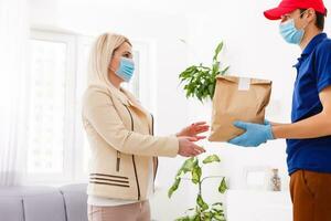 Corriere nel protettivo maschera e medico guanti consegna porta via cibo. consegna servizio sotto quarantena, malattia scoppio, coronavirus covid-19 pandemia condizioni. foto