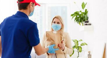 Corriere nel protettivo maschera e medico guanti consegna porta via cibo. consegna servizio sotto quarantena, malattia scoppio, coronavirus covid-19 pandemia condizioni. foto