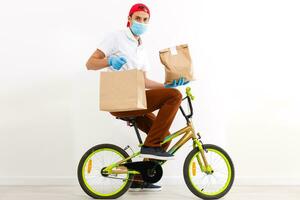 un' uomo nel protettivo maschera è consegna cibo su un' bicicletta. in linea shopping e esprimere consegna . quarantena foto