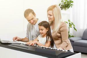 contento famiglia, madre, padre e figlia giocando pianoforte a casa, concetto per famiglia relazione. musica scuola e musica famiglia. foto