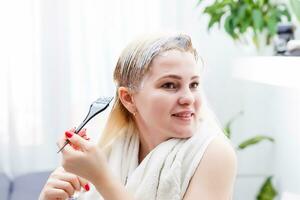 un' di mezza età donna coloranti sua capelli a casa, in casa foto