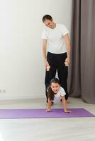 bello giovane padre e il suo carino poco figlia siamo fare riverbero tavola con gamba aumentare su il pavimento a casa. famiglia fitness allenamento. foto