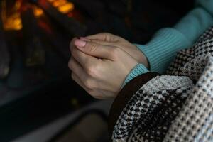 giovane donna riscaldamento mani vicino camino a casa. concetto di riscaldamento stagione. foto