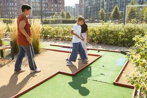 gruppo di sorridente amici godendo insieme giocando mini golf nel il città. foto