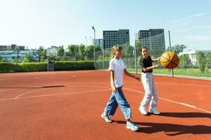 bambini e gli sport. adolescenziale ragazza giocando pallacanestro su il terreno di gioco. foto