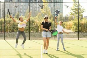 attivo giovane donna praticante padel tennis con gruppo di Giocatori nel il tennis Tribunale all'aperto foto