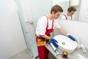 un' lavoratore installa un' lavare bacino nel un' bagno. foto