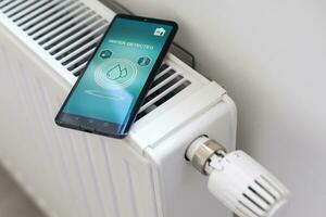 smartphone con lanciato applicazione per aria temperatura registrazione di fronte il termosifone. Salute microclima a casa concetto foto