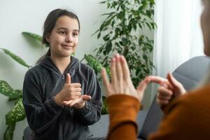 figlia parlare con mezzo anziano madre persone utilizzando cartello linguaggio, famiglia seduta su poltrona lato Visualizza, insegnante insegnare adolescente sordomuto ragazza per visualmanual gesti simboli concetto Immagine foto