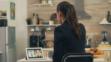 donna d'affari utilizzando un' tavoletta per video chiamata durante prima colazione. giovane libero professionista nel il cucina parlando su un' video chiamata con sua colleghi a partire dal il ufficio, utilizzando moderno Internet tecnologia foto