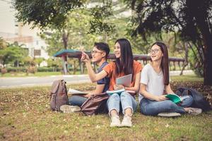 gruppo di studenti universitari asiatici che leggono libri e insegnano lezioni speciali per l'esame sul campo in erba all'aperto. felicità e educazione concetto di apprendimento. torna al concetto di scuola. tema adolescenti e persone foto