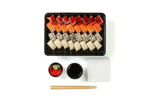 un' impostato di Sushi nel un' consegna scatola, soia salsa, bacchette, wasabi, Zenzero su un' bianca sfondo foto