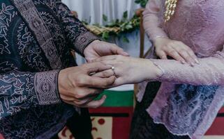 sposo mette un' squillare su il sposa dito. cerimonia e nozze pianificazione. oro anelli per musulmano spose nel Indonesia. foto