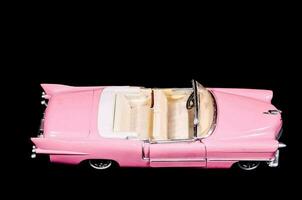 un' rosa giocattolo auto è mostrato su un' nero sfondo foto