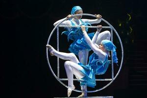 Due acrobata ragazze mostrare un' circo numero su un' buio sfondo. acrobatico prestazione. foto